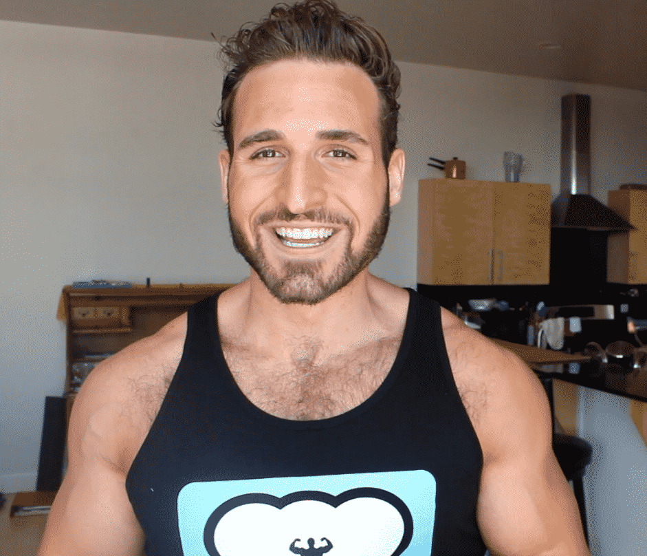 A man smiling in front of a kitchen.