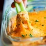 Low carb buffalo chicken wing dip being pulled out of a tray with celery.