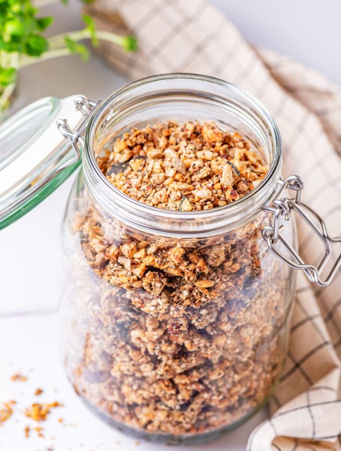 Granola in a glass jar on a white table.