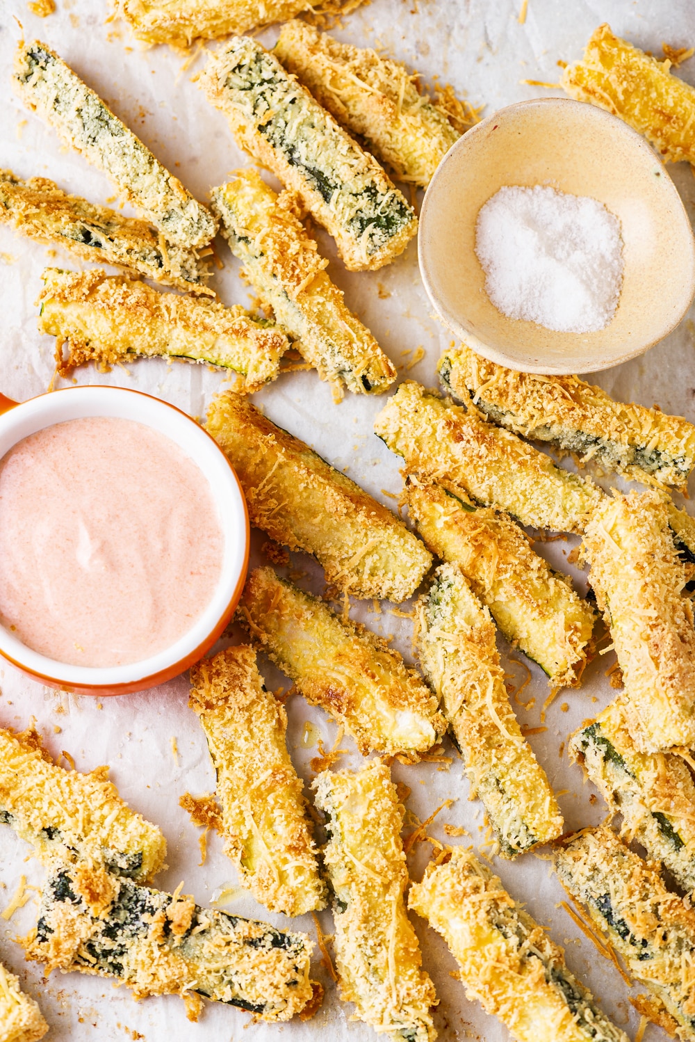 Zucchini fries on a tray with two small cups of dipping sauces.