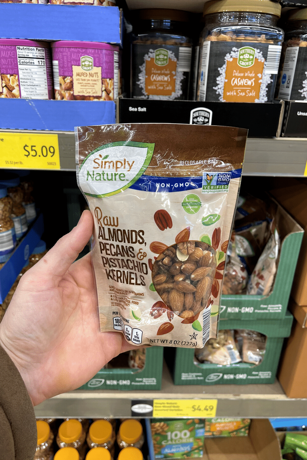 A hand holding a package of mixed nuts.