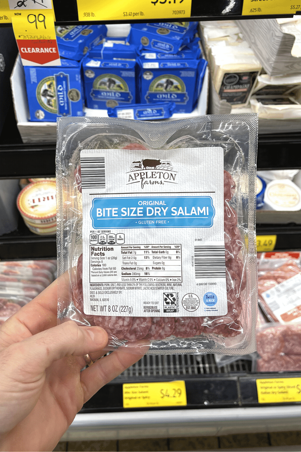 A hand holding a package of bite sized salami.