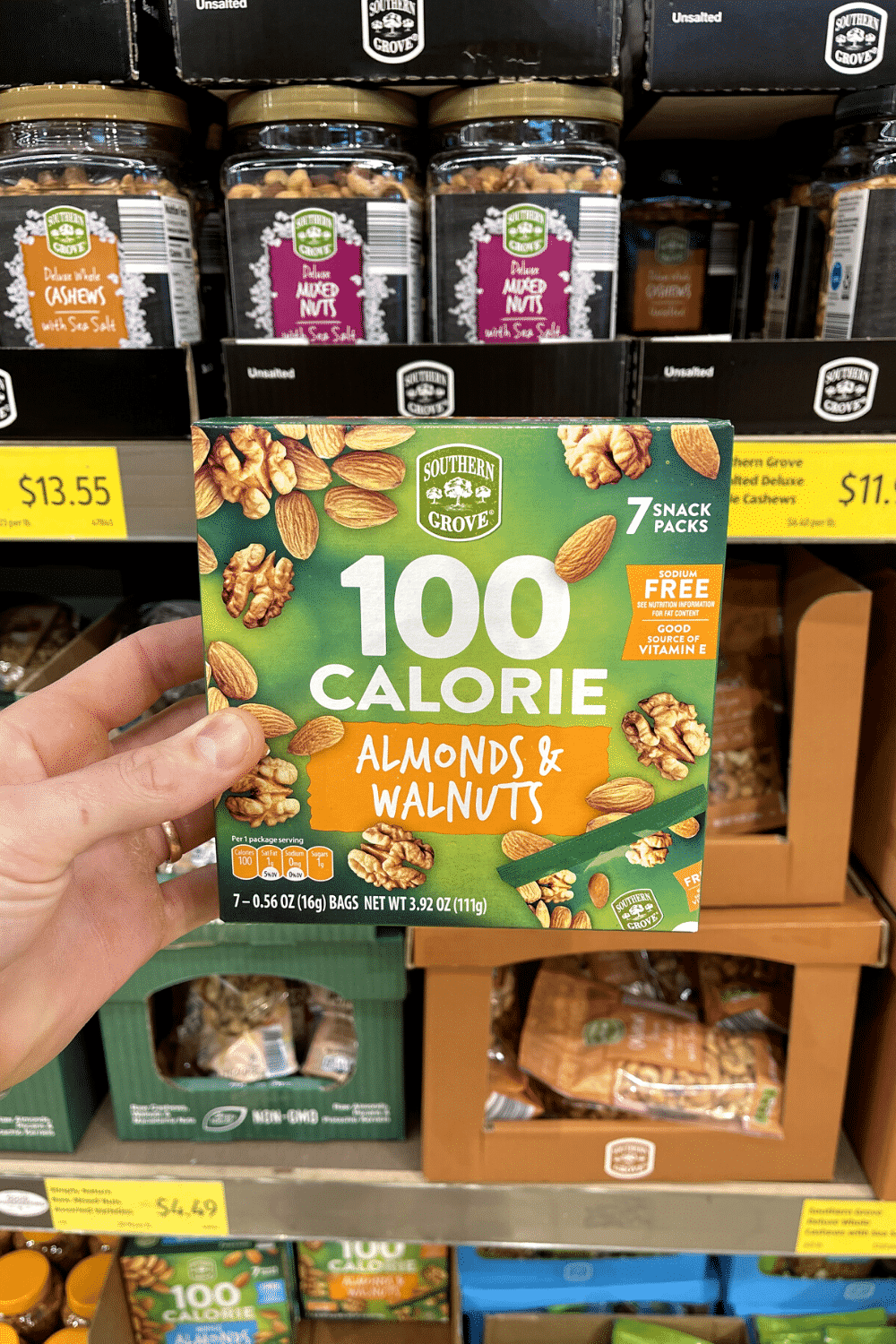 A hand holding a box of walnut and almond snack packs.