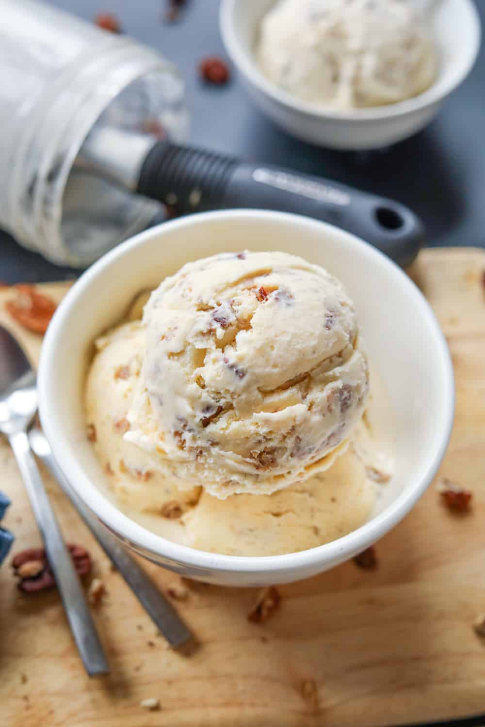 3 Scoops of ice cream in a white bowl that's set on a tan cutting board.