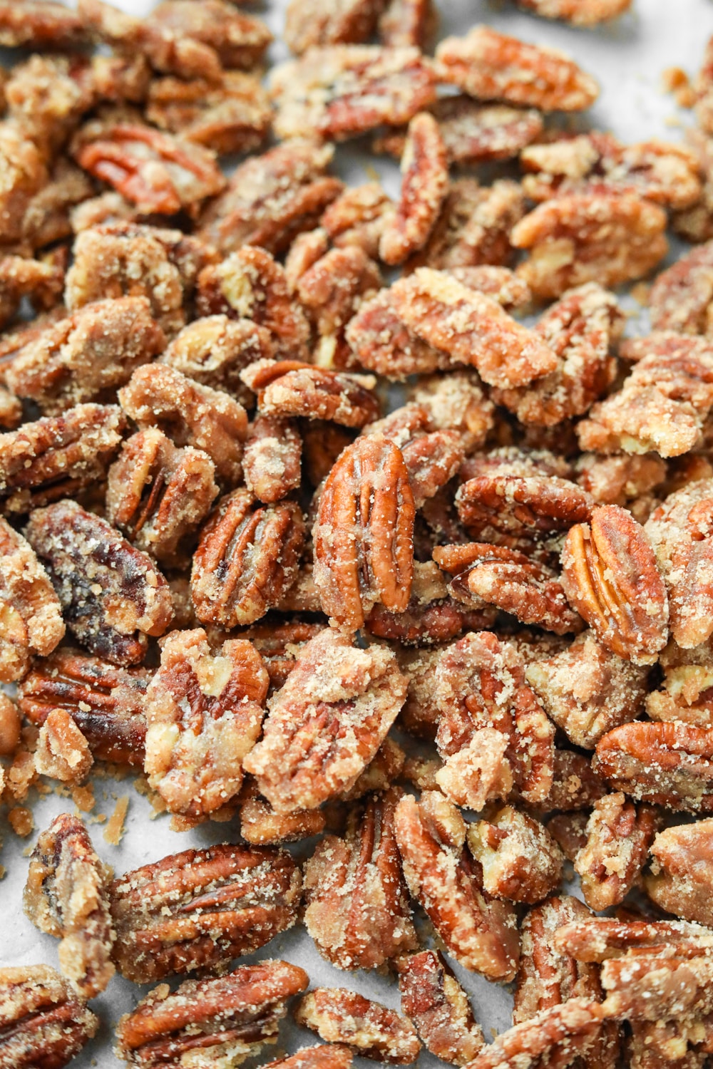 Candied pecans on a white sheet of parchment paper.