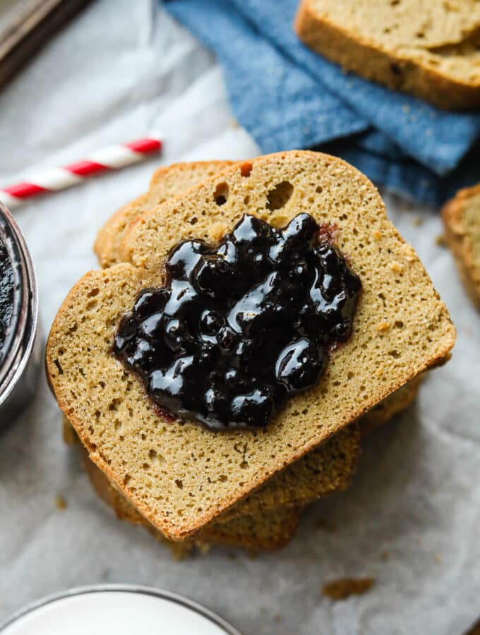 A slice of nut butter bread covered in grape jelly.