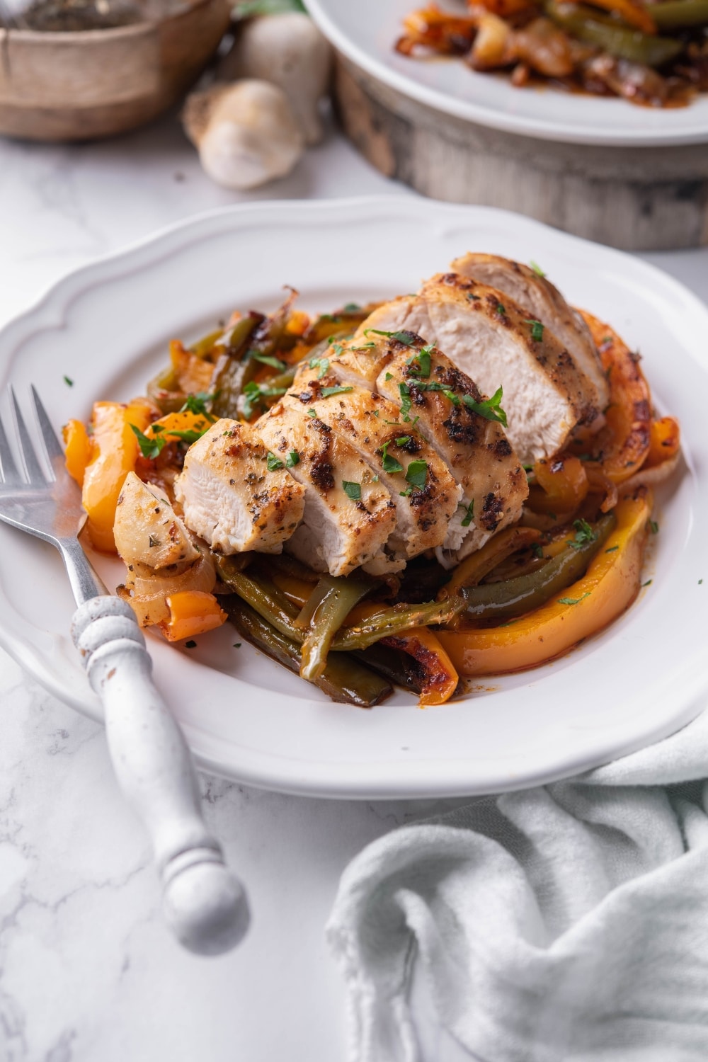 Baked chicken and bell peppers on a white plate with a fork.