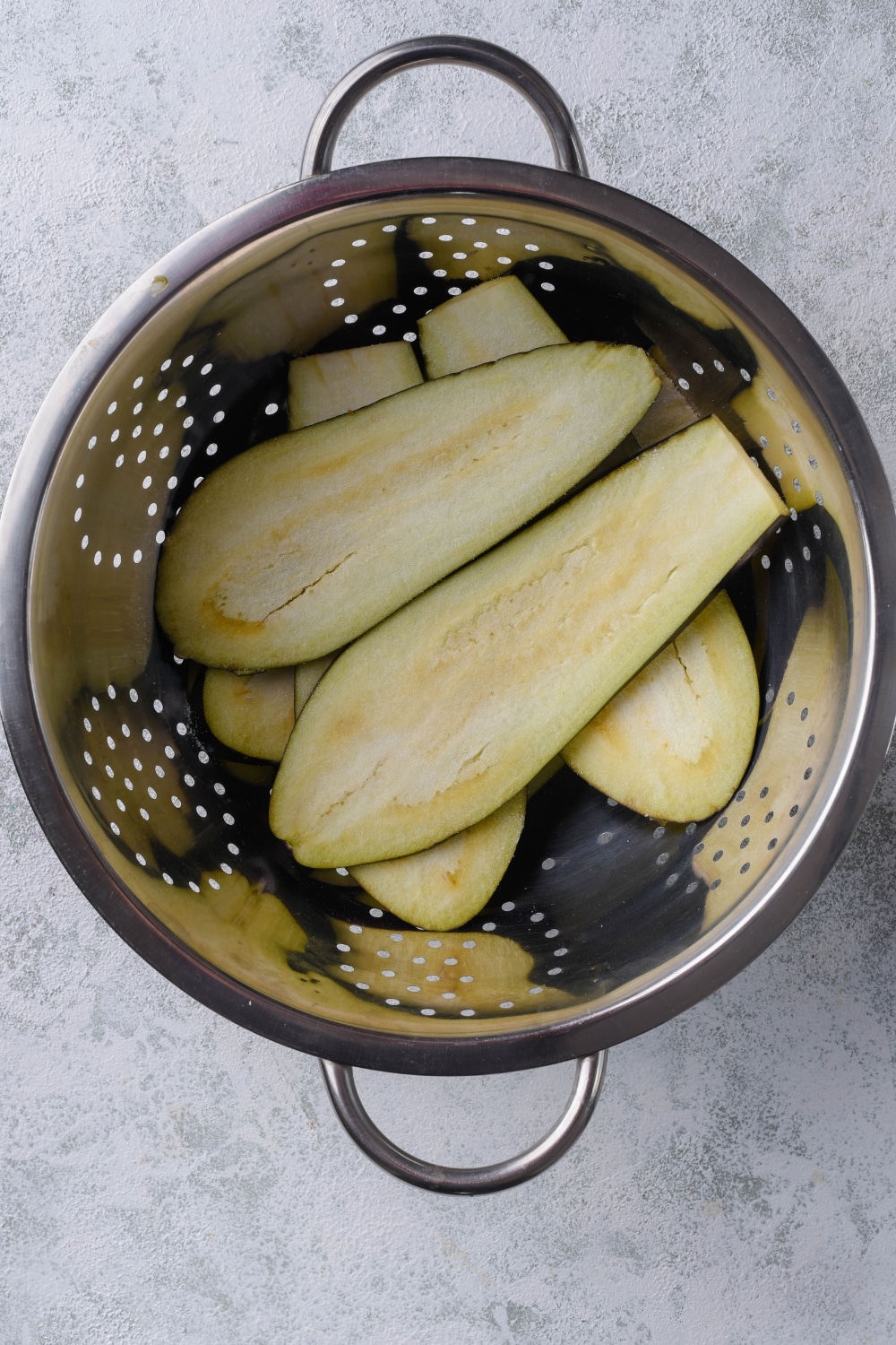Eggplant slices in a colander.