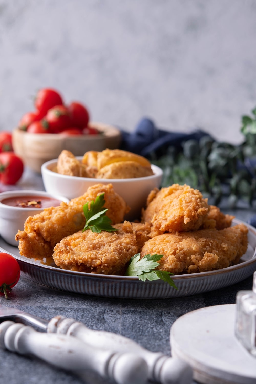 A few chicken tenders overlapping one another on a grey plate.