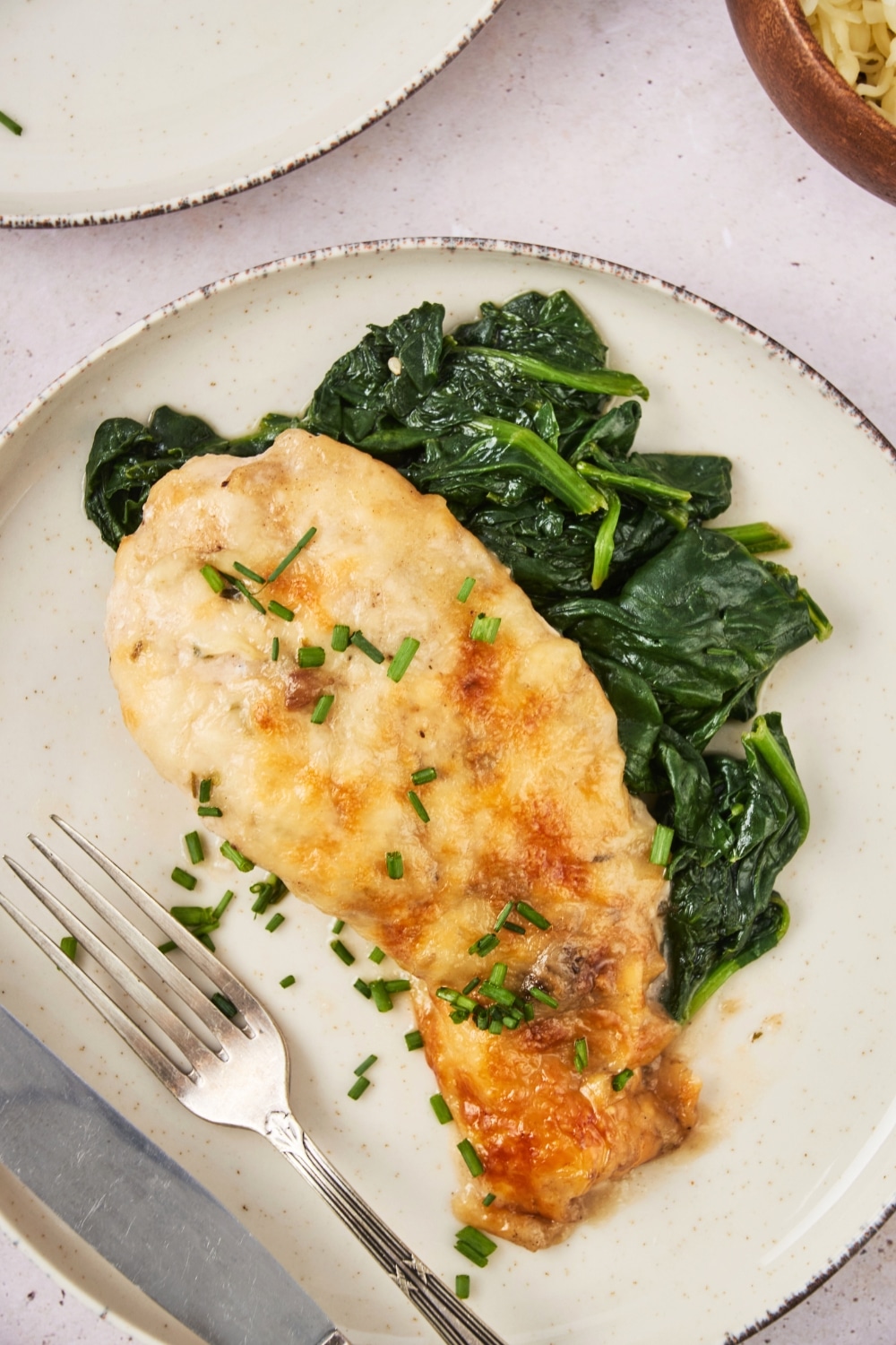A piece of mushroom baked chicken on top of collard greens on a plate.