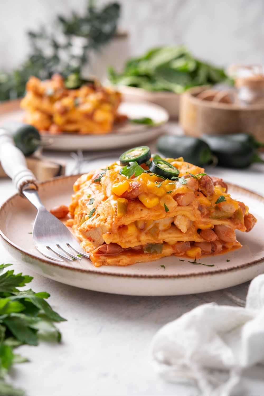 A square of enchilada casserole on a white plate that has four layers.