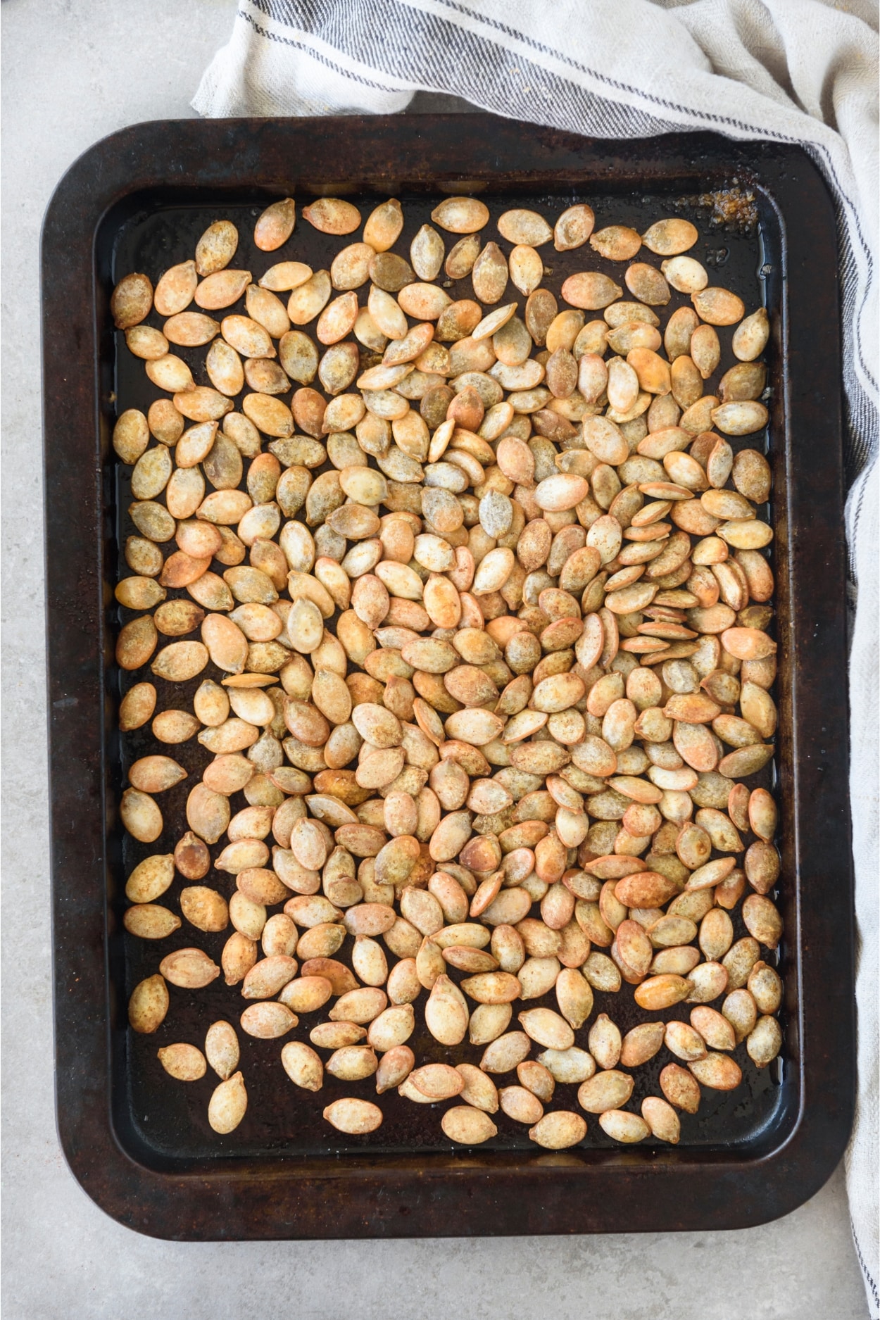 Roasted pumpkin seeds covering an entire baking sheet.