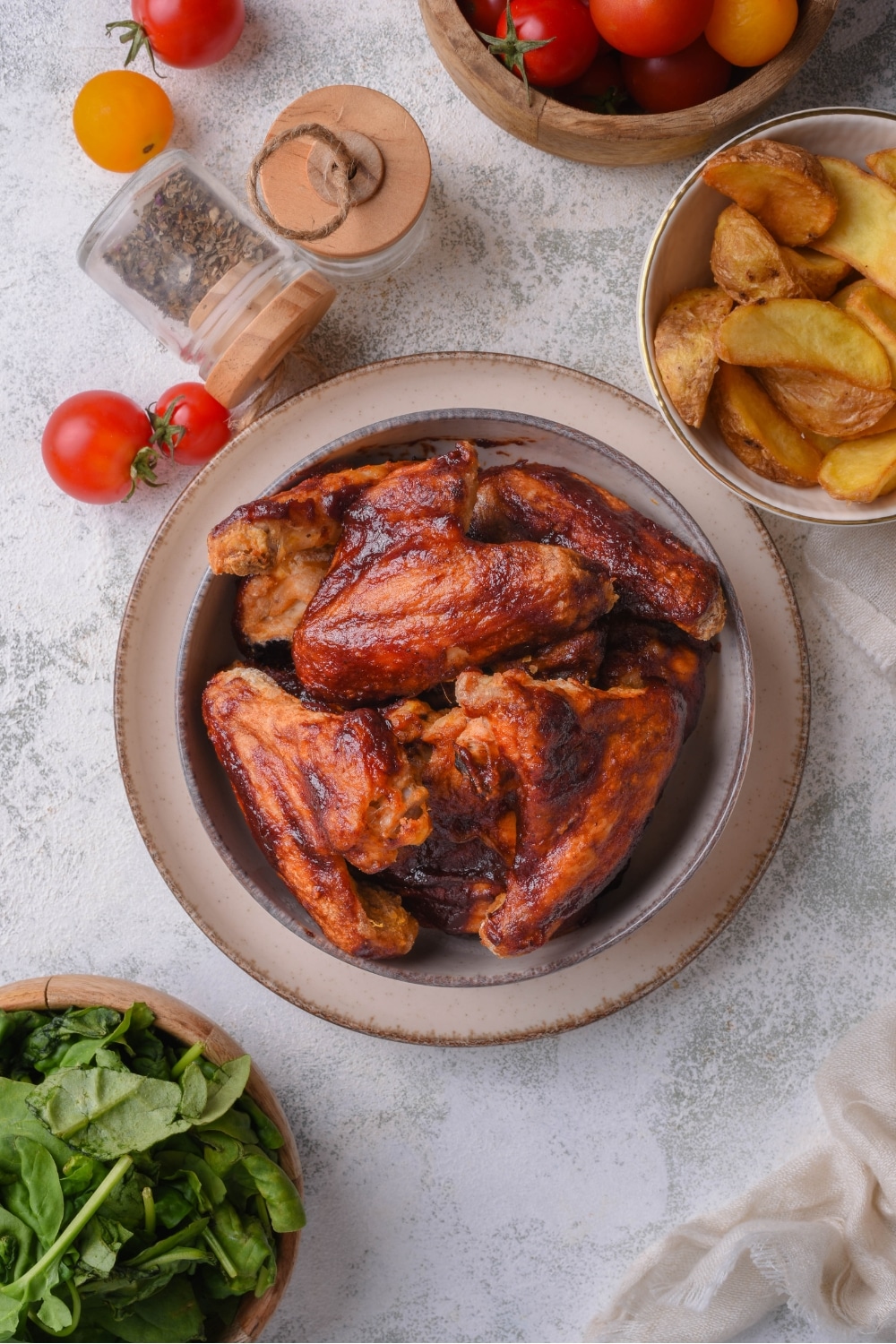A bunch of bbq chicken wings in a bowl on top of a plate on a counter.