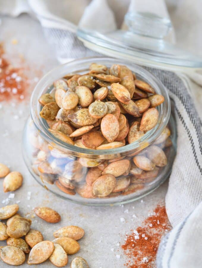 A glass jar that is filled with pumpkin seeds.