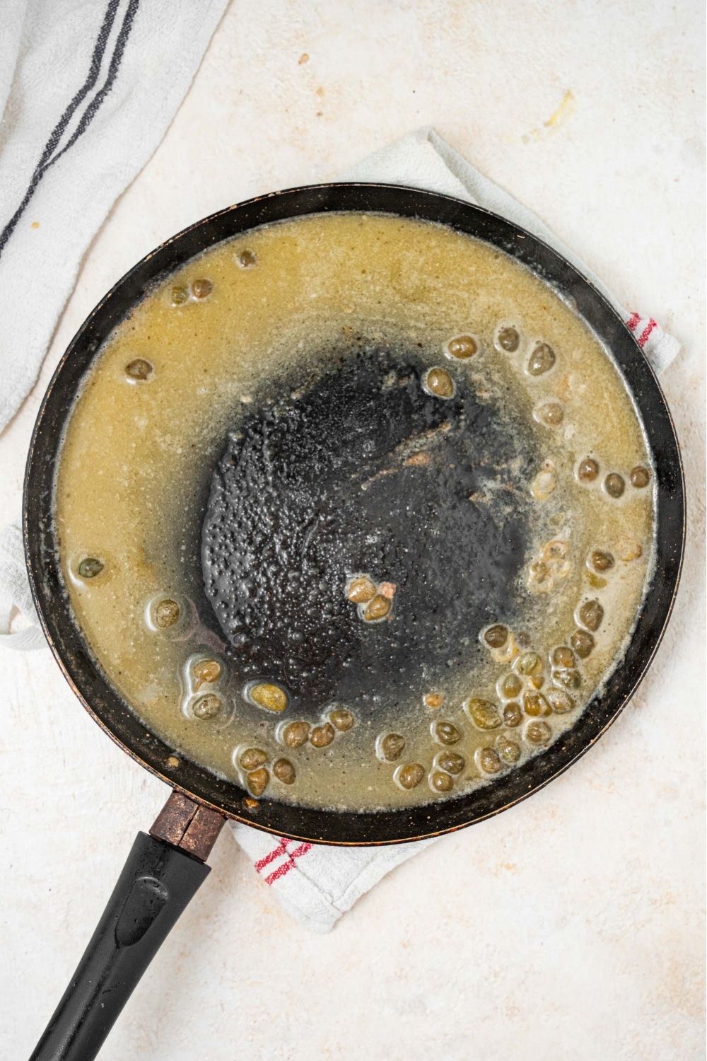 An overhead shot of a large skillet cooking a lemon caper sauce.
