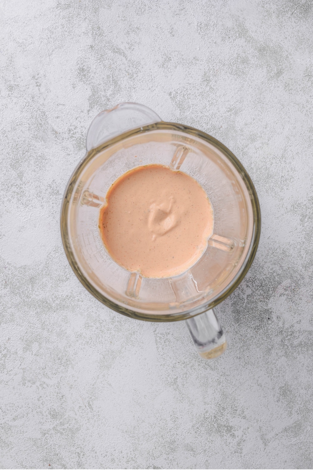An overhead shot of a glass blender with blended low calorie big mac sauce.