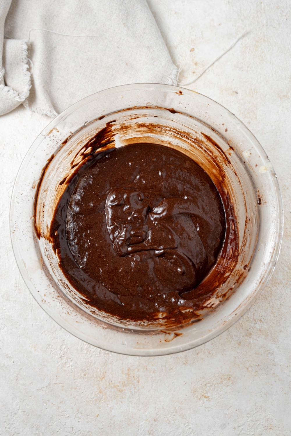 Overhead view of a clear bowl filled with chocolate cake batter.