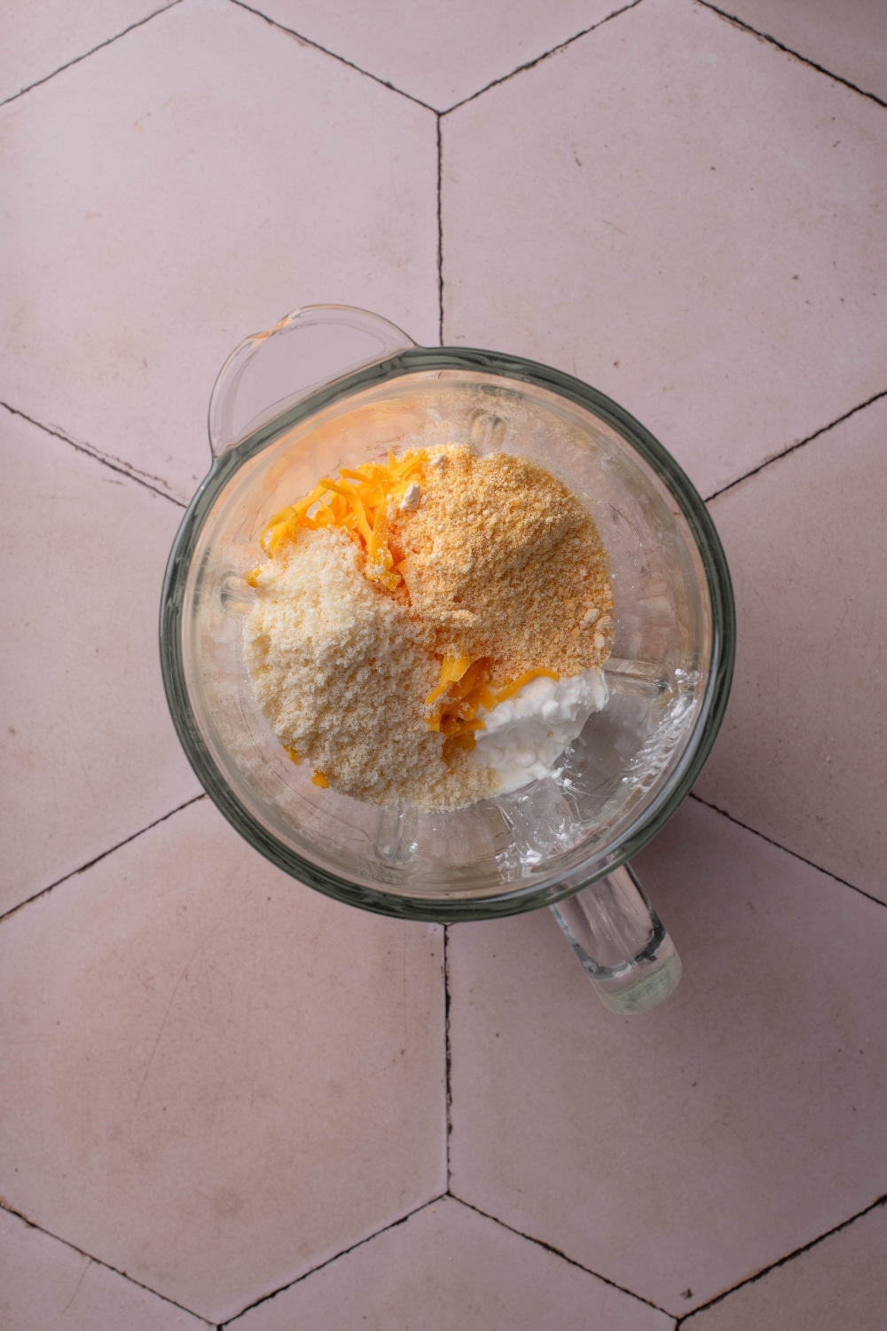 A blender filled with shredded cheese, cottage cheese, and seasonings.