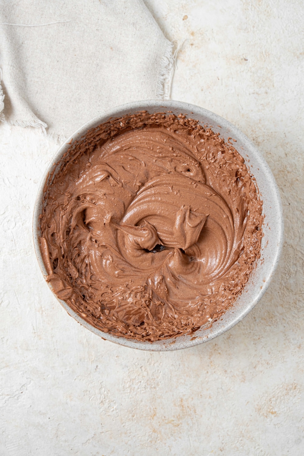 Overhead view of a grey bowl filled with chocolate frosting.