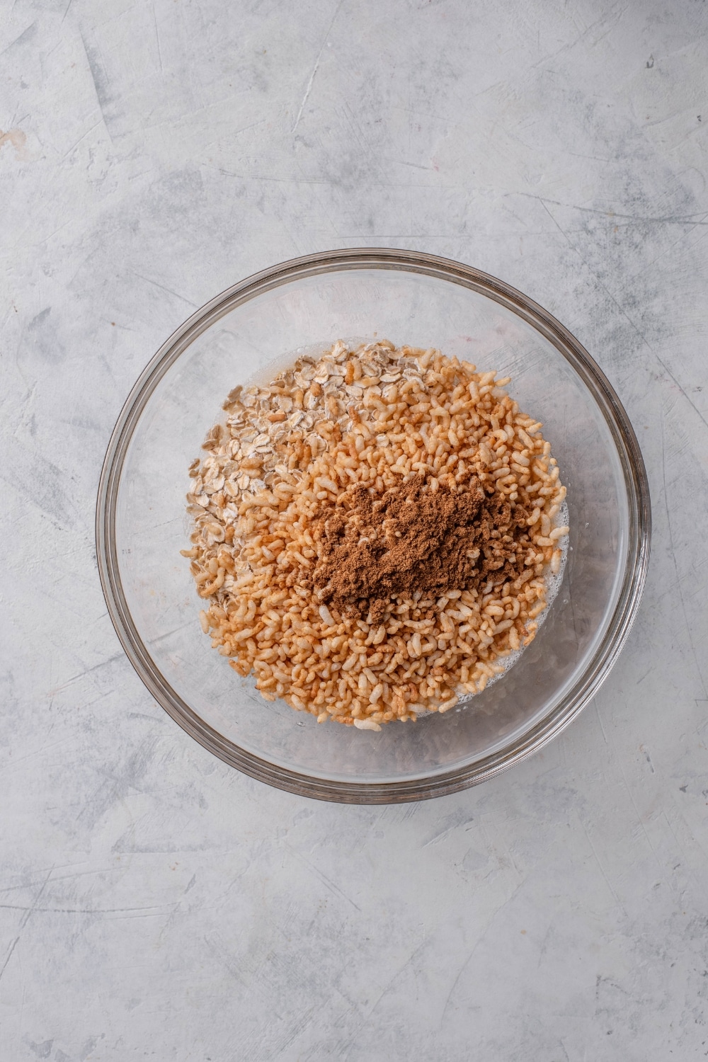A clear bowl filled with brown rice cereal, oats, and cinnamon.