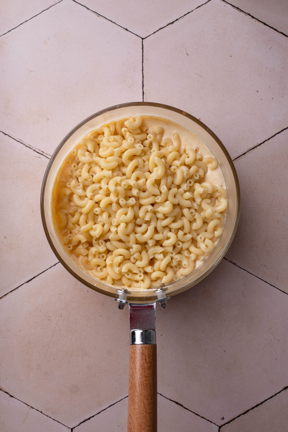 A pot filled with cheese sauce and macaroni noodles piled on top of the sauce.