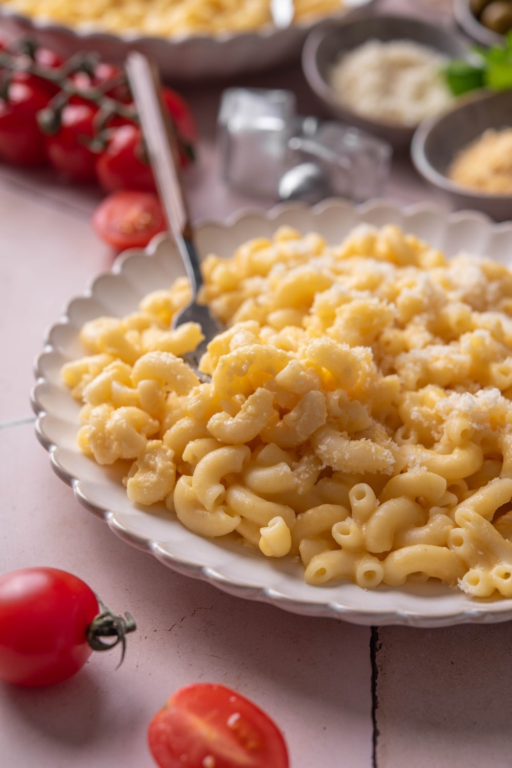 A plate of mac and cheese topped with grated cheese. There is a fork on the plate.