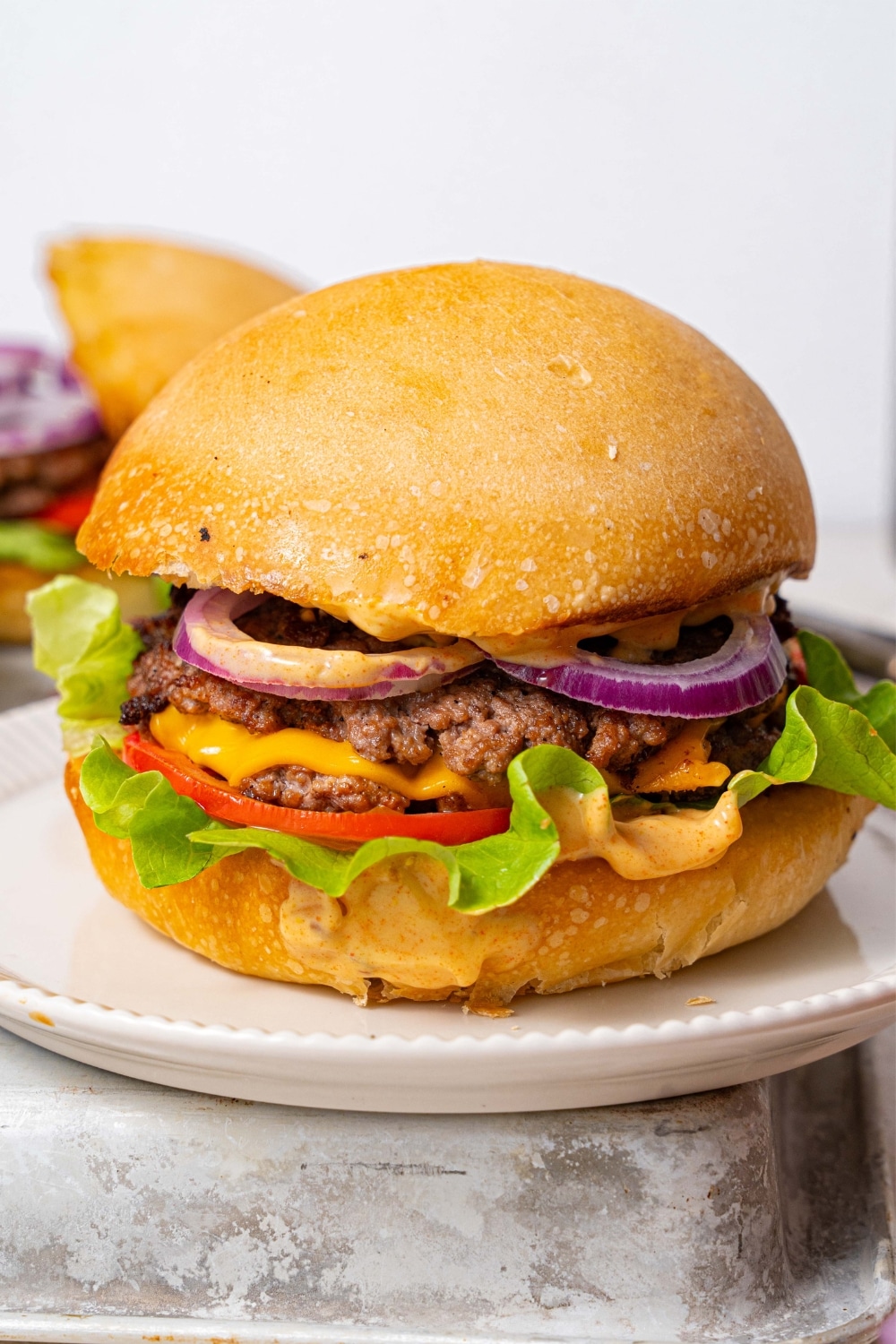 A smash burger filled with smashed burger patties, cheese, red onion slices, tomato slices, lettuce, and burger sauce.