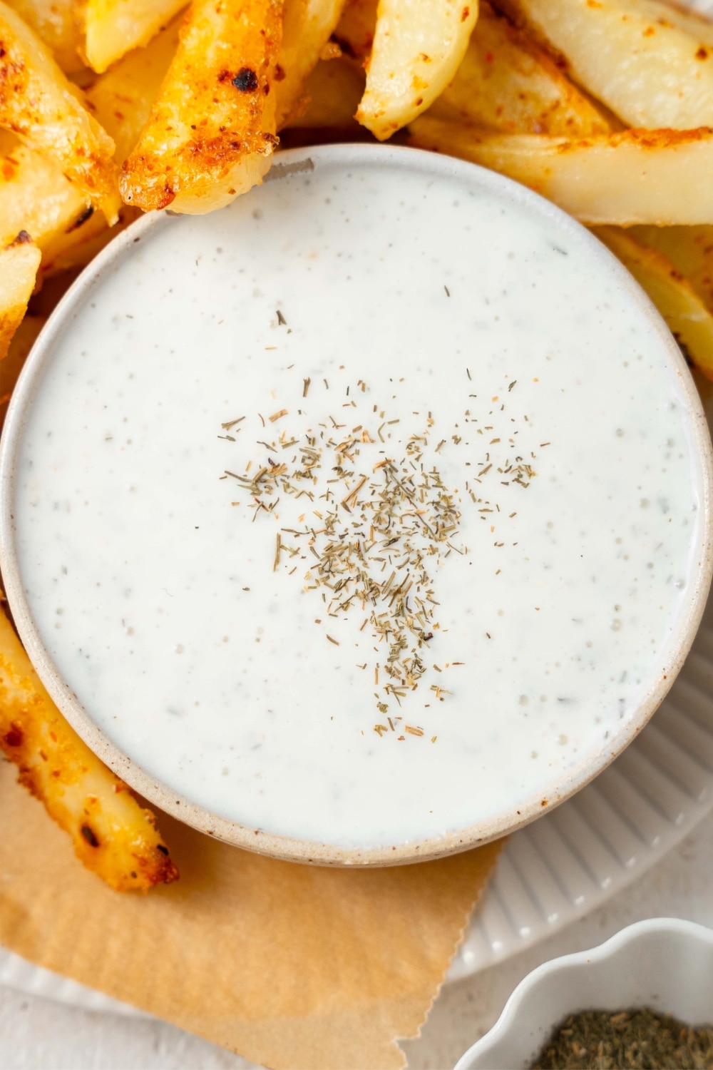 Cottage cheese ranch dip in a bowl, garnished with dry herbs and served with seasoned french fries.