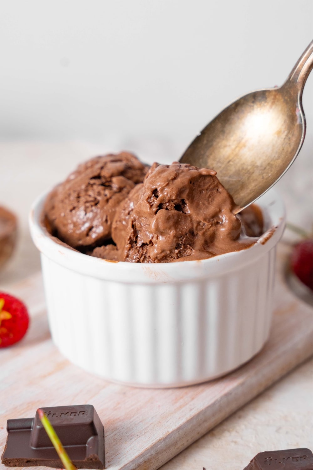 Chocolate cottage cheese ice cream in a ramekin being scooped with a spoon.