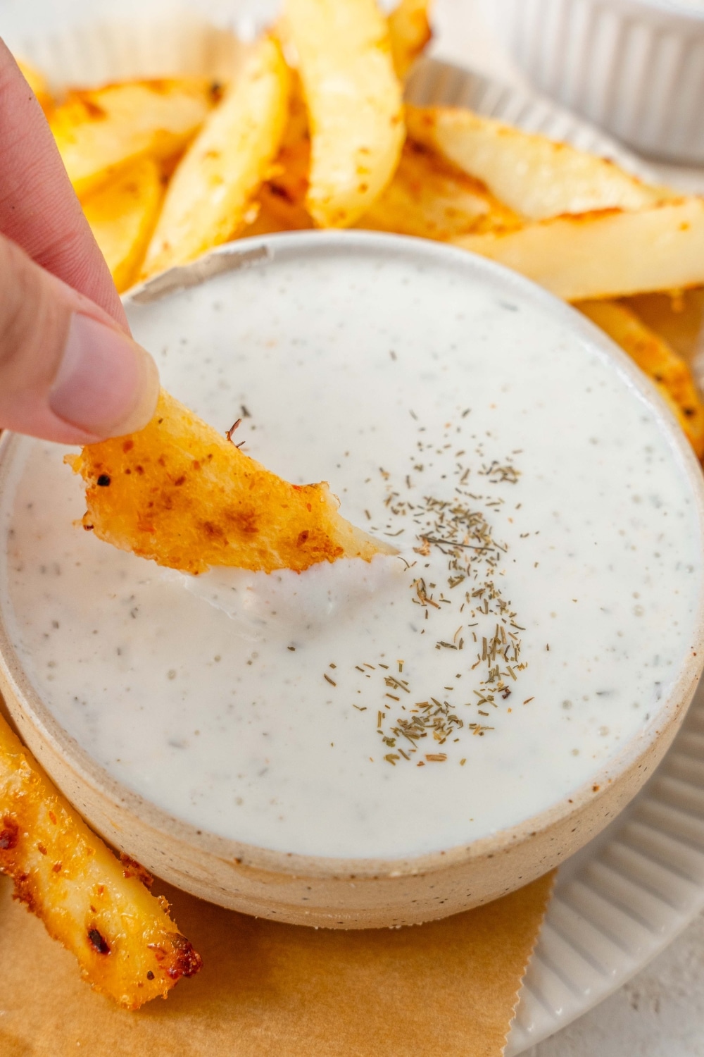 Dipping a seasoned french fry into a bowl of cottage cheese ranch dip.