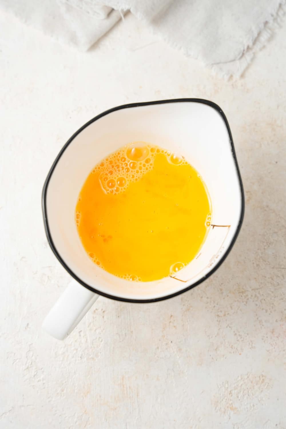 Whisked eggs in a ceramic measuring jug.