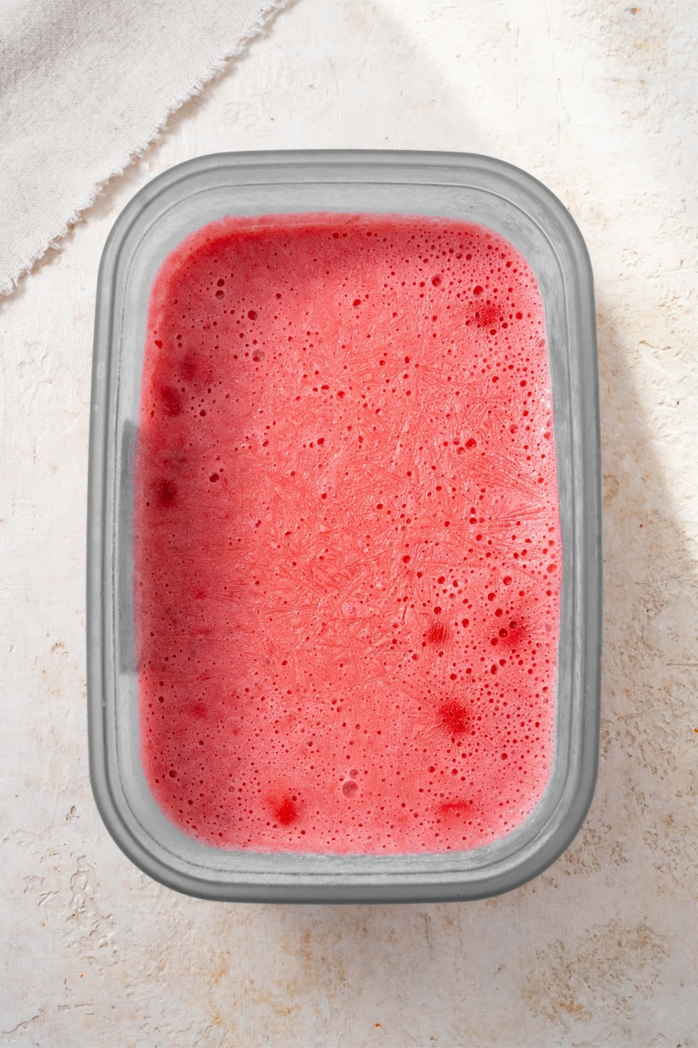 Strawberry cottage cheese ice cream in a tub.