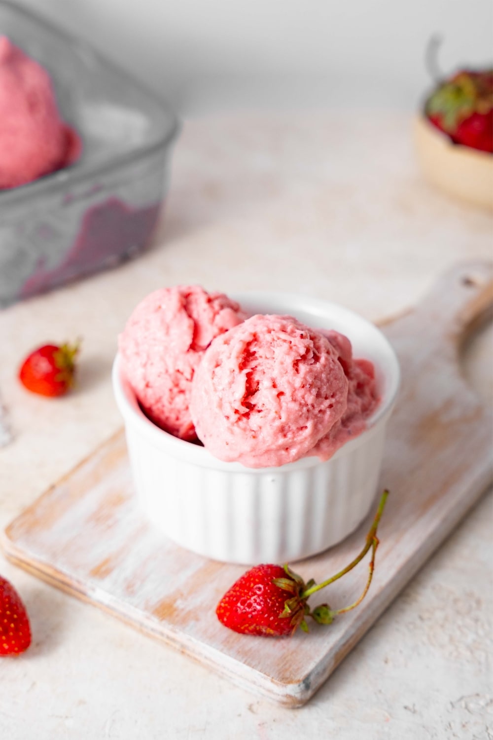 Strawberry cottage cheese ice cream in a bowl, surrounded by fresh strawberries.