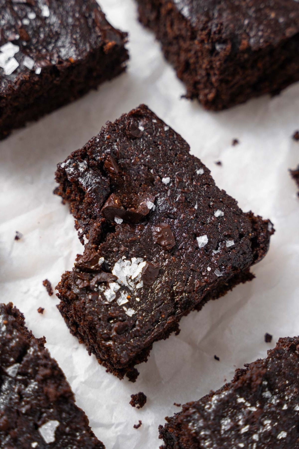 A closer look at one cottage cheese brownie garnished with flaky sea salt, with a bite taken out.