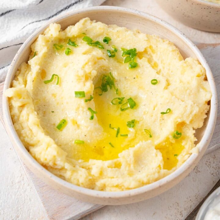 Cottage cheese mashed potatoes finished with chopped chives and melted butter in a bowl.