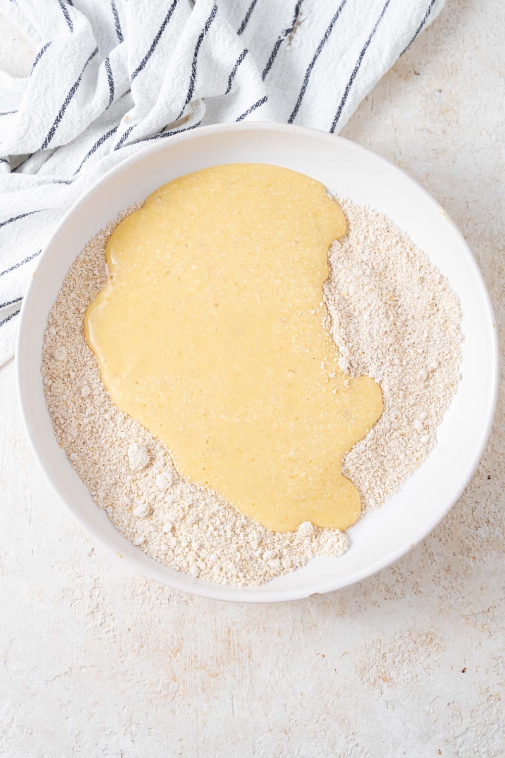 Wet and dry cottage cheese banana blueberry pancake batter ingredients unmixed in a white bowl.