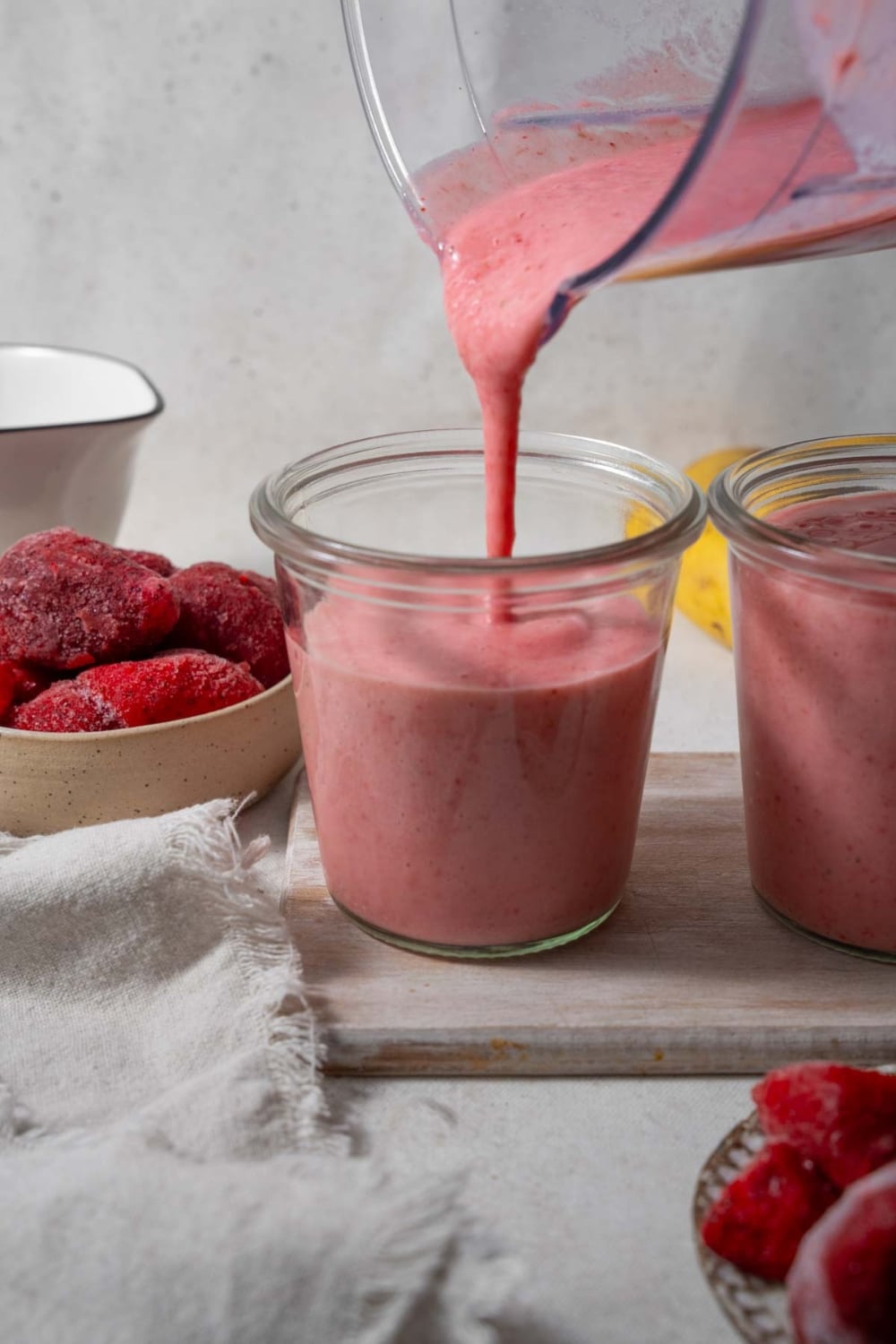 Pouring strawberry cottage cheese smoothie into a glass.